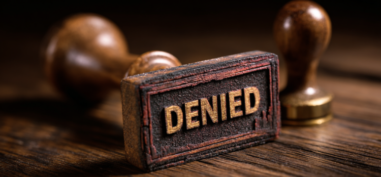 A stamp on a wooden desk that has the word "denied" on it